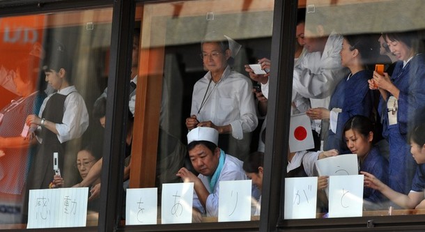 Workers and patrols gather near windows to watch Japan' фото