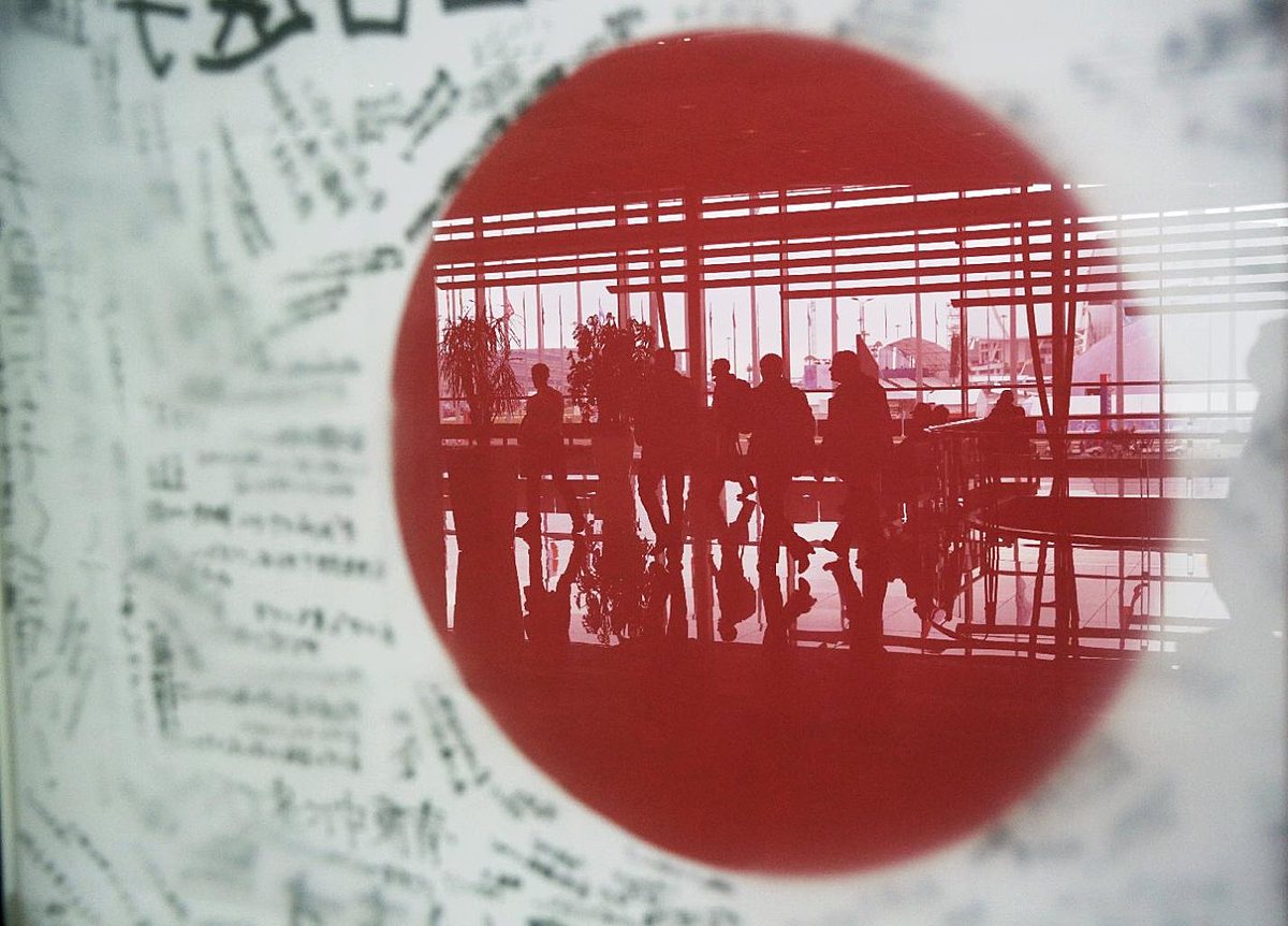 Speedskating fans are reflected in a window, with a Japanese фото (photo)
