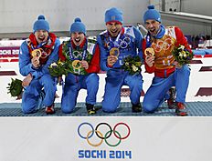 Russia's relay team celebrate during flower ceremony for men's biathlon 4 x 7.5 km relay at Sochi 2014 Winter Olympic Games